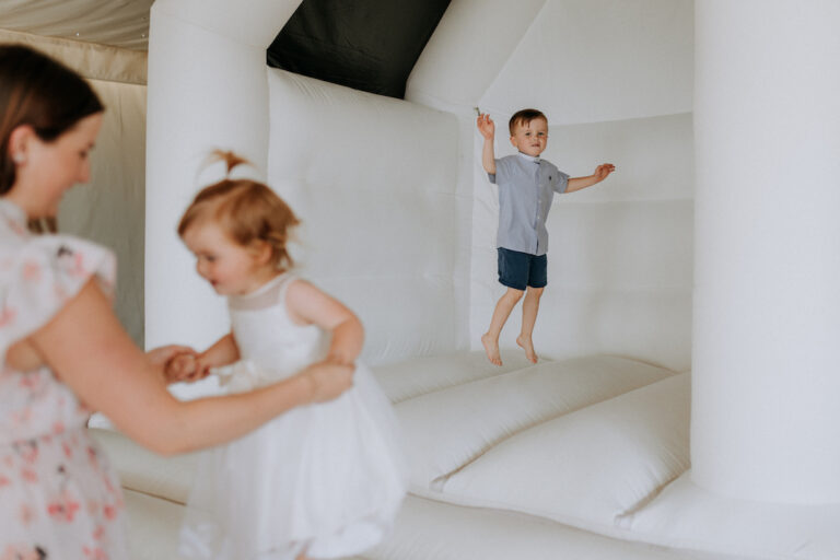 Small children playing on a white bouncy castle during a christening