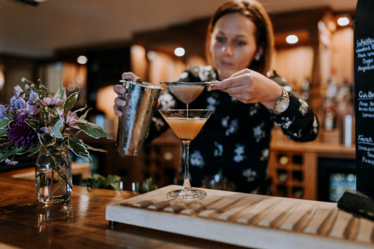 A woman making a summery cocktail on the bar at The Ferry House 2AA Rosette restaurant in Kent.