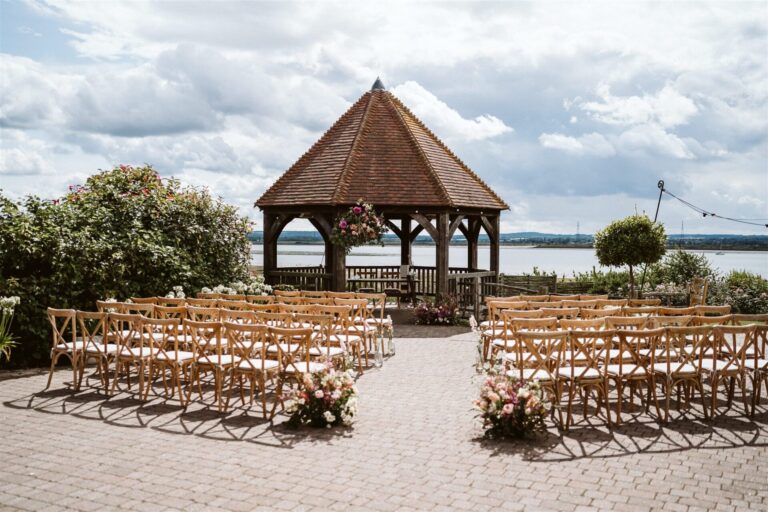 An outdoor wedding ceremony set up in The Ferry House in Kent, overlooking the water.