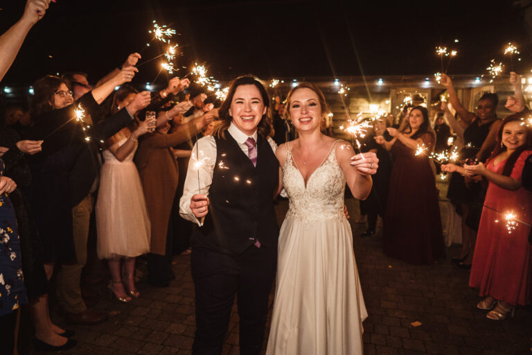 A wedding couple holding sparklers outside The Ferry House wedding venue at twilight