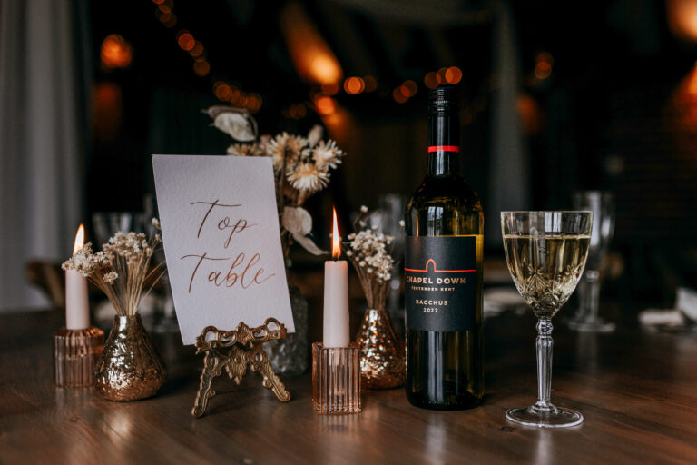 Top table of a wedding celebration with wine on the table and candles.