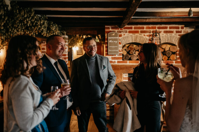 Guests at The Ferry House barn wedding venue in Kent enjoying the drinks reception in the private pub.
