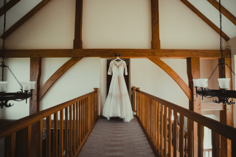 A brides wedding dress hanging in the hallway of The Salting's cottage at Mocketts Farm Cottages.