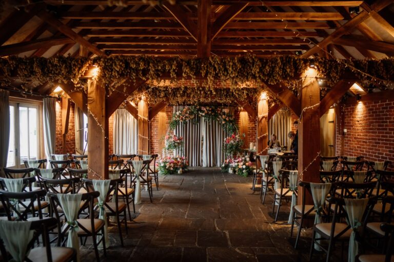 A beautiful barn wedding ceremony with cross back chairs and flower arch.