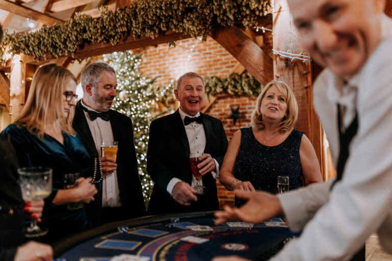 A casino table and surrounded by laughing guests at a party.