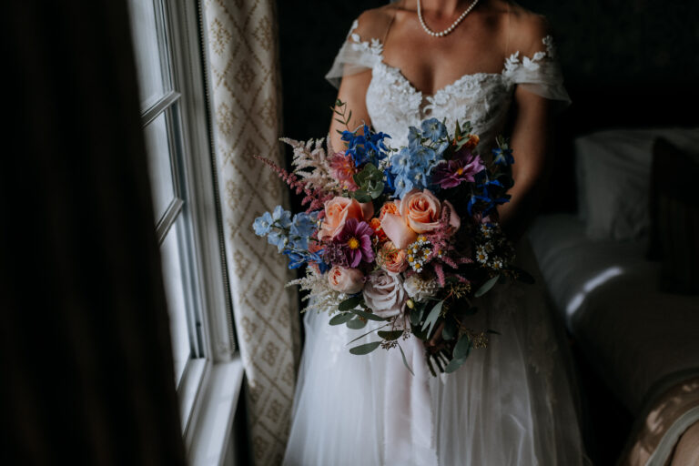 A bride holding a colourful bouquet for her barn wedding at The Ferry House in Kent.